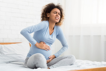 African-american pregnant lady suffering from stomach spasms