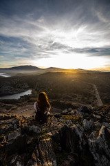 Beautiful woman standing on a cliff during sunset at Cap de Creus, Spain