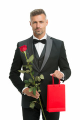 male elegance. valentine man black tux suit. man with present for love date. Black tie for formal events. tuxedo man with rose and shopping bag. happy valentines day. gift with love. shopping sale