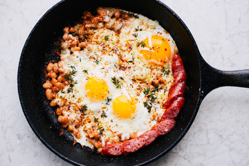 Homemade hot fried eggs with vegetables, cheese and sausage close up 