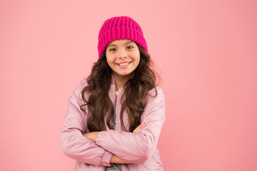 good mood any weather. cheerful child in warm winter clothes. seasonal fashion for kids. small beauty pink wall. girl puffer jacket and knitted hat. health care in cold weather. Full of happiness