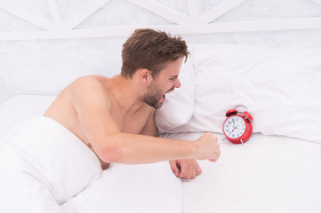 man angry because alarm rings. Angry man lying in bed early in morning. stop ringing. Sleep longer....