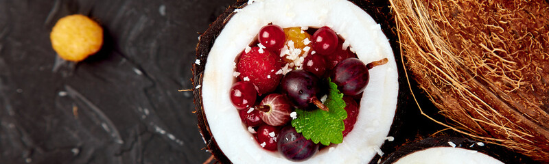 Banner of Fruit salad agrus, gooseberry, rasbberry in coconut shell bowl