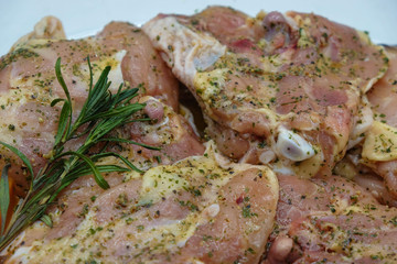 Fresh chicken thighs marinated with fragrant herbs isolated with a branch of rosemary. Ukrainian cuisine.