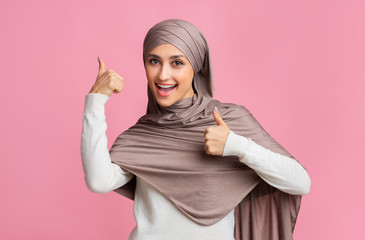 Happy Muslim Girl In Hijab Gesturing Thumb Up With Both Hands