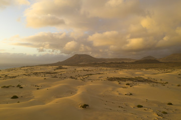 Fototapeta na wymiar Desert volcano with sand dunes and golden sky