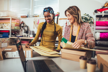 Sales Online. Working women at their store. They accepting new orders online and packing merchandise for customer.