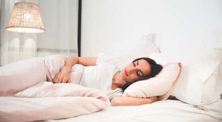 Safe and sound. Close-up photo of a gorgeous girl, who is sleeping in her bed on peach-colored...