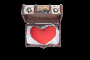 The red heart lies in a wooden box. Black background. Isolated image.