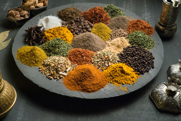spices on a dark background surrounded by oriental dishes, top view