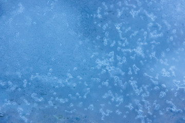 Texture of blue ice with small air bubbles on the lake. Chaotic, imperfect, contaminated