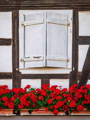 Closed window blinds on a half-timbered house with a flower box