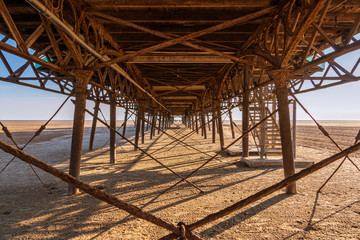 Obraz premium Standing under the rusty iron construction on the downside of a pier