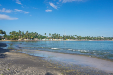 Tropical beach with ships and palm trees on the Sri Lanka island. Turquoise sea with a low tide.