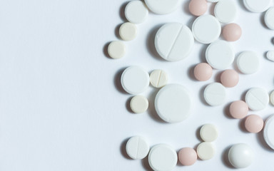 Heap of pills, pharmaceutical medicine tablets and capsules on white background. Drug prescription for treatment medication health care concept, top view with copy space.