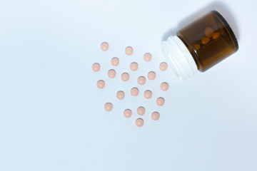 pink medical pills and tablets spilling out of a drug bottle on the white background, top view with copy space for text, health care pharmaceutical medicine concept .