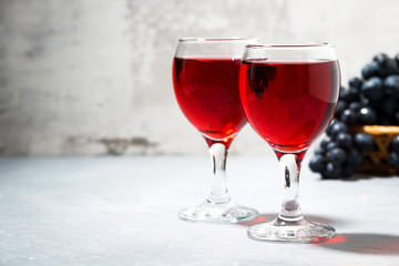 two glasses of red wine on a gray background
