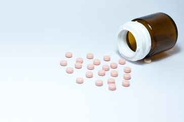 pink medical pills and tablets spilling out of a drug bottle on the white background, top view with copy space for text, health care pharmaceutical medicine concept .