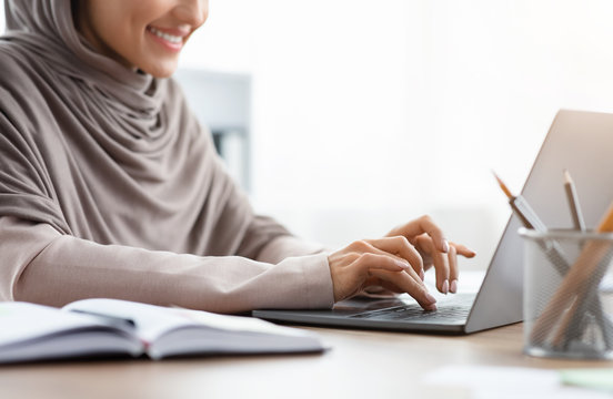 Unrecognizable Muslim Woman In Headscarf Working On Laptop In Office