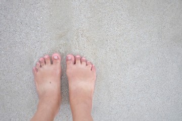 A female barefoot on sand beach with wet background and copy space