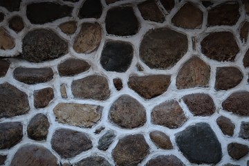 Fototapeta premium The surface is made of flat stones of black and brown shades, bonded with white plaster.