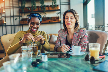 Two female friends talking at a coffee shop.