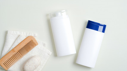 Hair care products design concept. SPA cosmetic bottle containers, wooden hair comb, white towel, organic soap on green background. Minimalist cosmetic product mockups, natural branding.