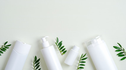 Natural organic cosmetic packaging set. Frame border of SPA cosmetic bottle containers mockups with green leaves. Minimalist flat lay style, top view. Skin care, hair care, SPA treatment concept