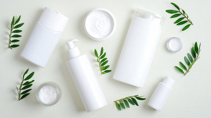 Cosmetic bottle packaging and jars with natural organic cream on green background with leaves....