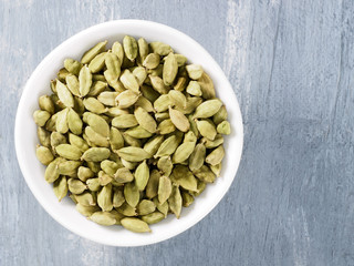 Spice green cardamom (Elettaria cardamomum) in a ceramic white bowl. Modern apothecary, naturopathy and ayurveda concept