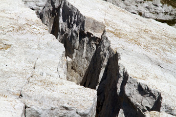 Fototapeta na wymiar Weiße scharfe Felsen, Felswand Textur aus Kalk Gestein in den Bergen der Dolomiten. Stein Struktur mit Risse und Kanten. Griffe zum Alpin Klettern