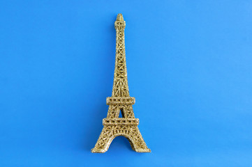 Fototapeta na wymiar Golden shiny eiffel tower figurine on a blue background.