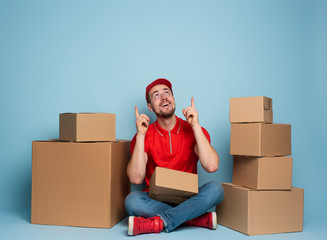 Courier is happy and indicates something above. Studio on cyan background