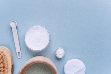 Creative top view flat bath composition, green spirulina, cleansing mask in a bowl, cream, body brush.