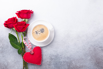Valentines day greeting card. Coffee cup, red roses and textile heart on stone background. Top view
