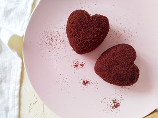 heart shaped cookies. Two heart-shaped chocolate cakes on a round pink plate, next to a textile napkin. Desserts for Valentine's day.