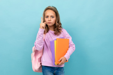 Beautiful schoolgirl in purple blouse thinks about studying isolated on blue background