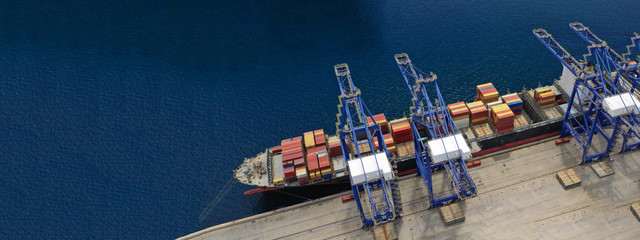 Aerial drone ultra wide top down photo of commercial container terminal with cranes loading...