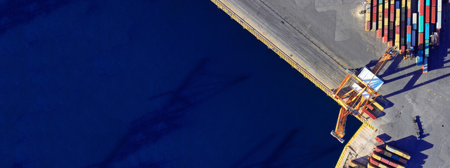 Aerial drone ultra wide top down photo of commercial container terminal with cranes loading...