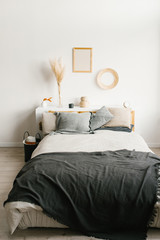 Fototapeta na wymiar Bed in the bedroom in a Scandinavian minimalist style. Gray pillows on the bed. Decor above the bed