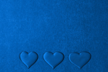 Top view of three hearts in row on cardboard background in classic blue color. Copy space, Valentines Day concept