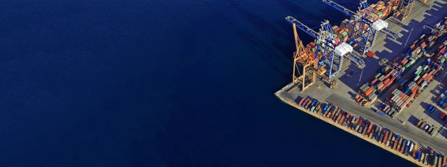 Fotobehang Luchtdrone ultrabrede top-down foto van commerciële containerterminal met kranen die zendingen laden naar tankschepen in de mediterrane haven © aerial-drone