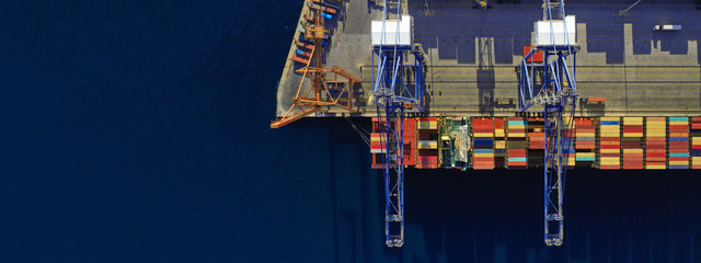 Aerial drone ultra wide top down photo of commercial container terminal with cranes loading...
