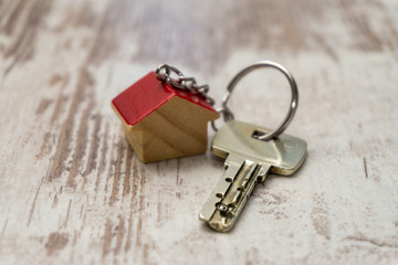 Schlüssel mit Schlüsselanhänger in Haus Form auf weißem Holz