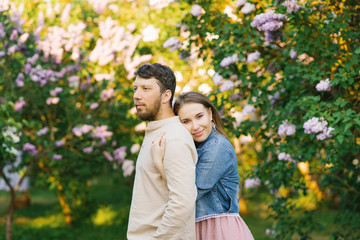 A romantic couple in love embrace in the spring in a blooming lilac garden