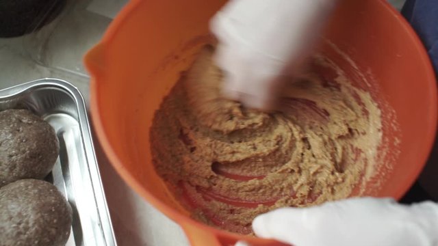 Footage of woman wearing white latex glove, knead sinced beef, making burgers