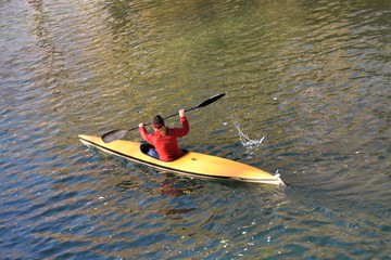 Side view of a sportswoman rowing in a kayak over calm waters
