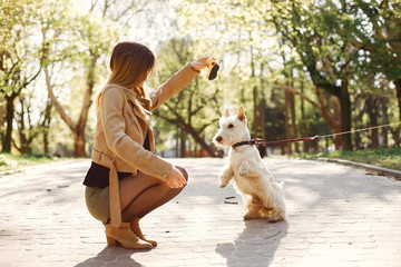 Obraz premium Beautiful girl in a black blouse. Woman in a summer park. Lady with cute dog