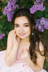 Beautiful young girl with professional makeup plus size in a blooming garden with big brown eyes