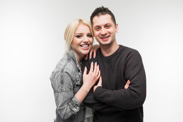 charming happy couple of a beautiful girl and a cute guy standing on a light gray background